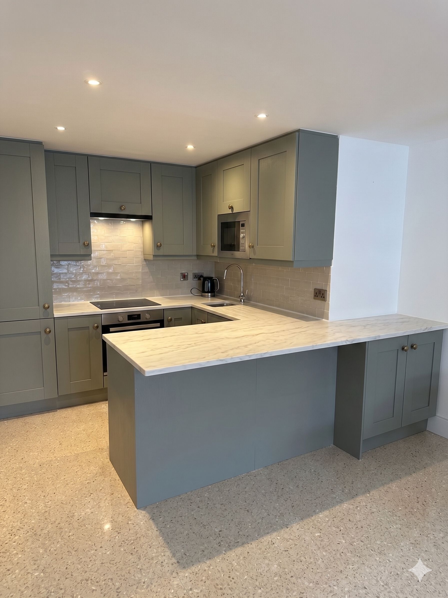 Une cuisine moderne avec des meubles gris, un grand îlot central et une hotte de cuisine en acier inoxydable.