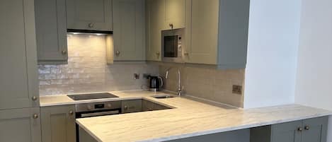 Une cuisine moderne avec des meubles gris, un grand îlot central et une hotte de cuisine en acier inoxydable.