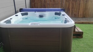 A hot tub with a control panel, surrounded by a wooden fence and a grassy area. - Villa 8pers, 3 chambres, Spa privatif, Climatisation, 4 Vélos, Plage & centre (Le Fenouiller)