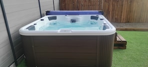 A hot tub with a control panel, surrounded by a wooden fence and a grassy area. - Villa 8pers, 3 chambres, Spa privatif, Climatisation, 4 Vélos, Plage & centre (Le Fenouiller)