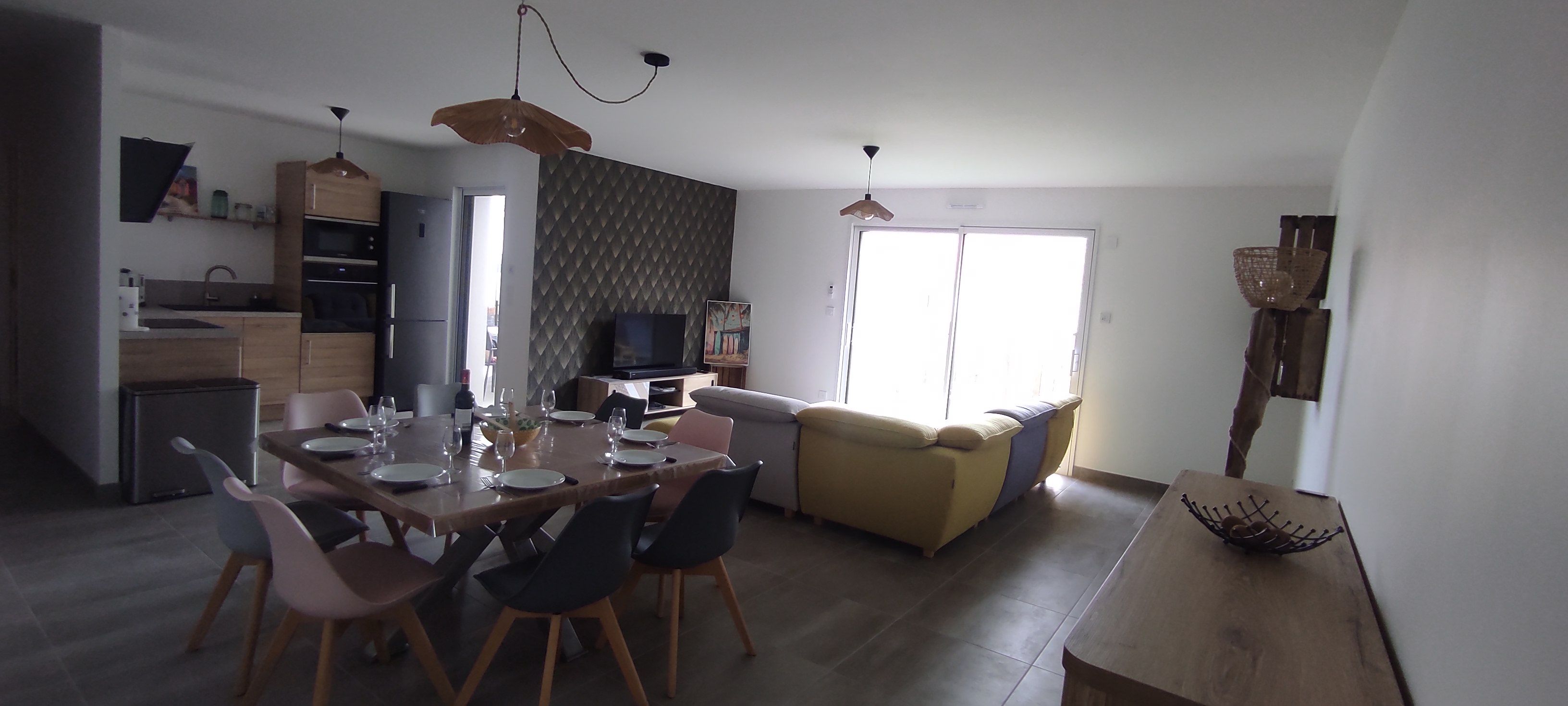 A modern kitchen with a dining area, a television, and a sofa.