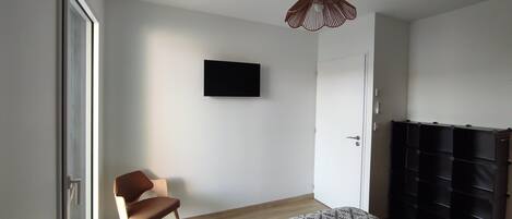 A room with a bed, a chair, a television mounted on the wall, and a wardrobe with multiple compartments.