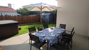 A patio with a table set for four, surrounded by chairs, under a large umbrella. - Villa 8pers, 3 chambres, Spa privatif, Climatisation, 4 Vélos, Plage & centre (Le Fenouiller)