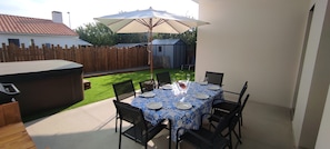 A patio with a table set for four, surrounded by chairs, under a large umbrella. - Villa 8pers, 3 chambres, Spa privatif, Climatisation, 4 Vélos, Plage & centre (Le Fenouiller)
