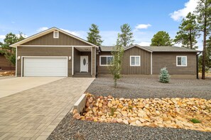 Ein zweistöckiges Haus mit Garage, überdachter Veranda und einem angelegten Vorgarten mit Felsenbeet.
