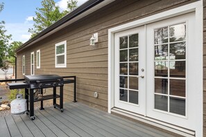 Ein Haus mit Terrasse, Grill und Schiebetür.
