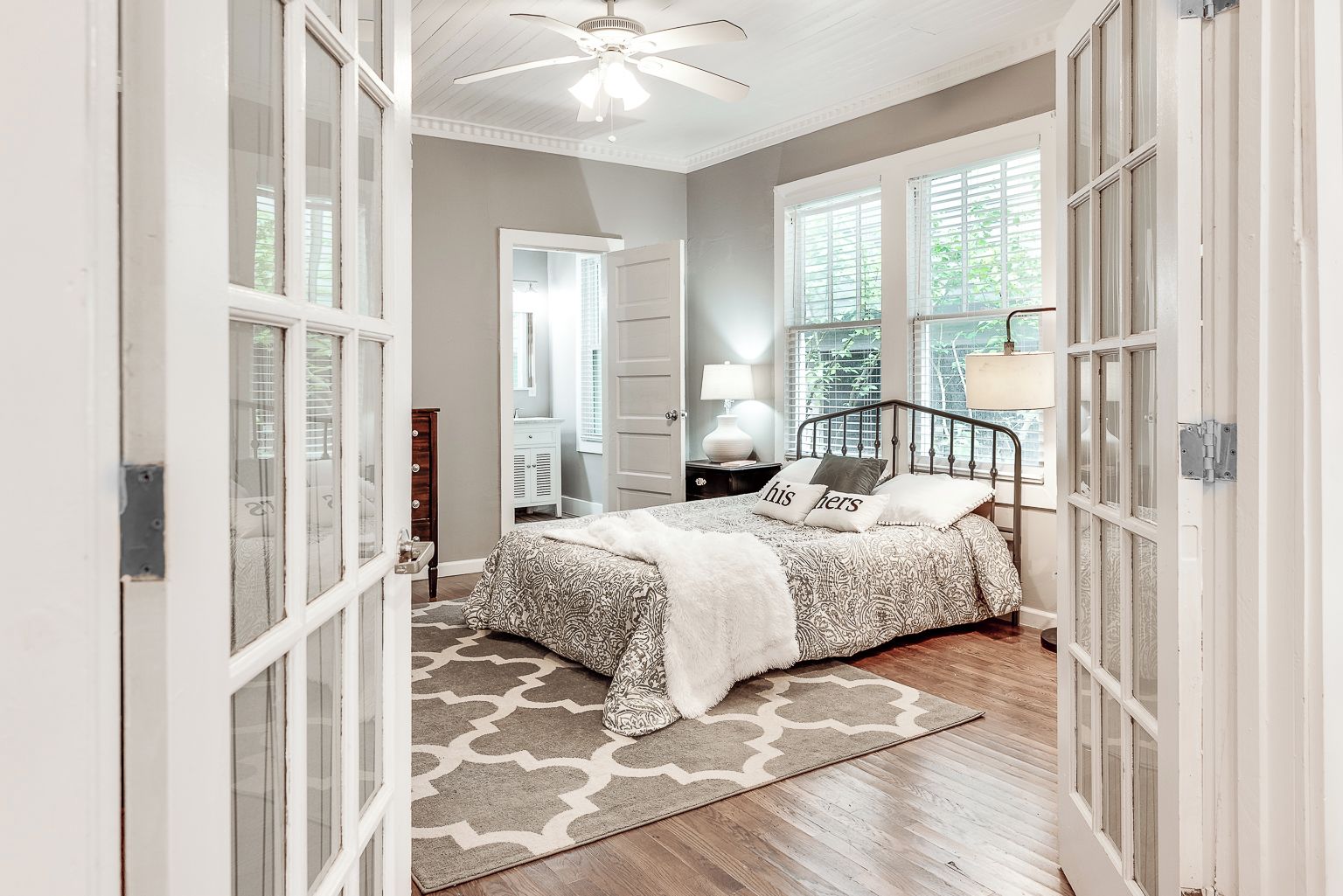 A bedroom with a bed, a bedside table, a lamp, and a window.