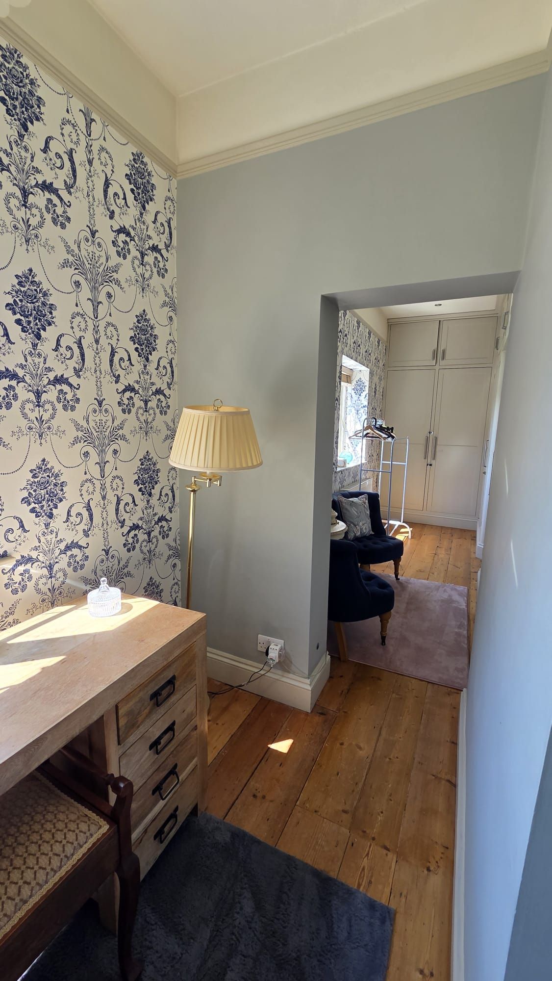 A room with a wooden desk, a lamp, a chair, and a wardrobe.
