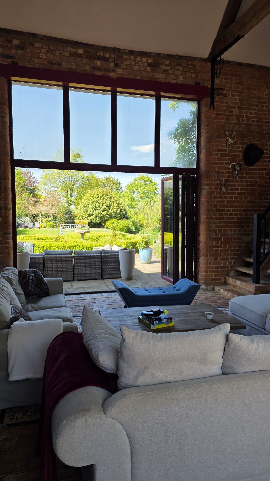 A spacious living area with a large window, a brick wall, and a view of a garden.