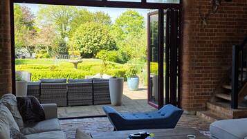 A spacious living area with a large window, a brick wall, and a view of a garden.