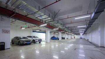 Garagem de estacionamento com vários andares, diversos carros estacionados, sinalização clara e ambiente limpo e bem iluminado.