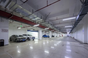 Un estacionamiento de varios niveles con varios coches aparcados, señalización clara y un ambiente limpio y bien iluminado.