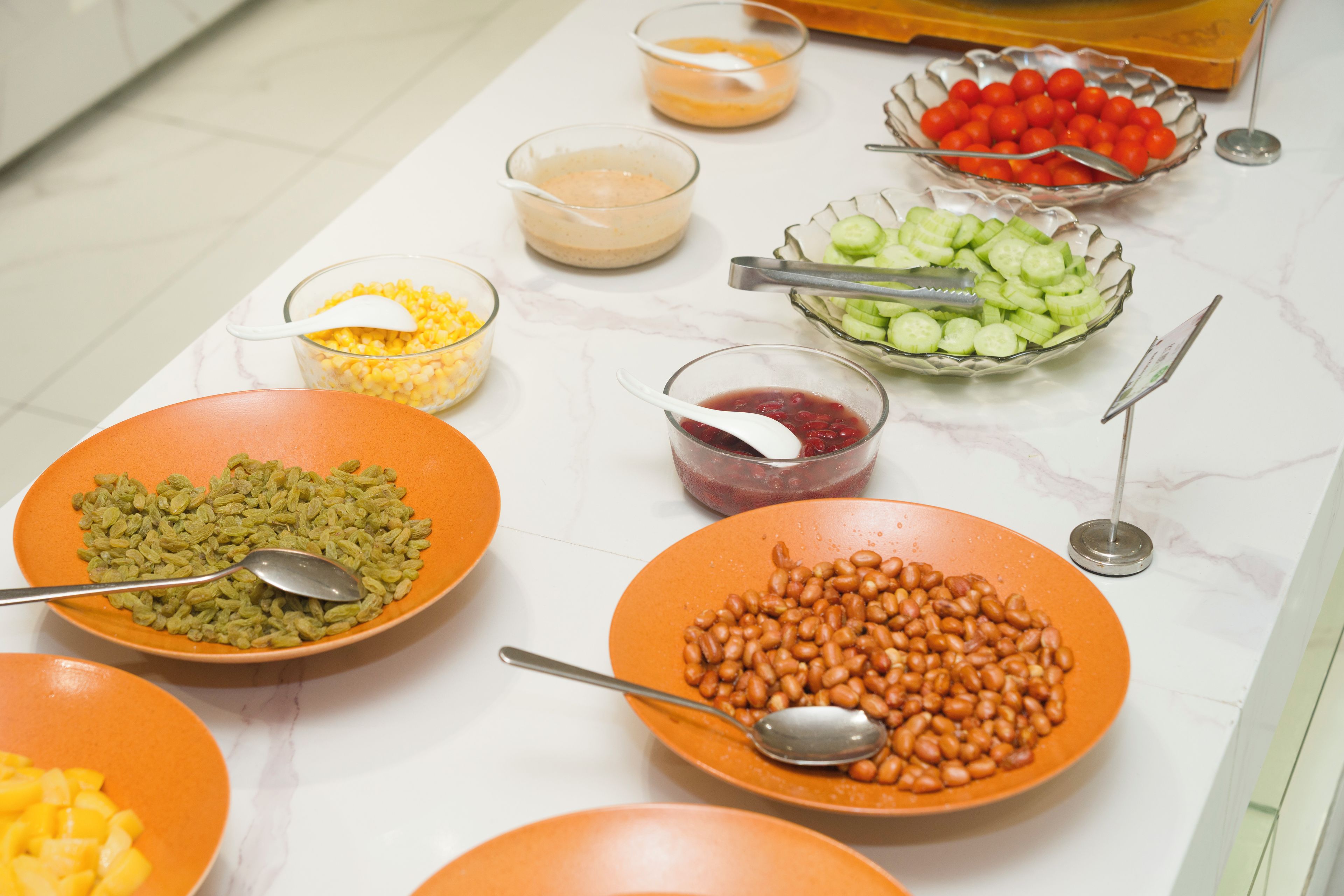 Une table de buffet proposant divers plats, notamment du maïs, des haricots et des légumes coupés en tranches.