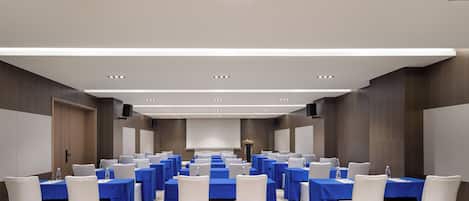 A conference room with rows of tables, chairs, and a podium.