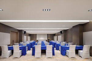 Un salón de conferencias con filas de mesas, sillas y un atril.