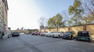 A parking lot with multiple cars and a building with a beige wall and windows.