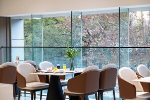 Un comedor moderno con ventanas amplias, varias mesas y sillas.