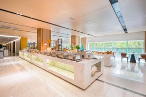 Un moderno vestíbulo de hotel con un mostrador de recepción de mármol, una vitrina de vidrio y una zona de estar con sillones.