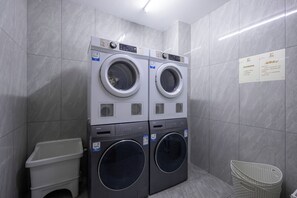 A laundry room with two stacked front-loading washing machines and a single dryer.