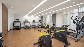Une salle de sport équipée de tapis de course, de vélos d’appartement et d’appareils de musculation.