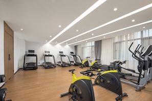 Un gimnasio con cintas de correr, bicicletas estáticas y máquinas de pesas.