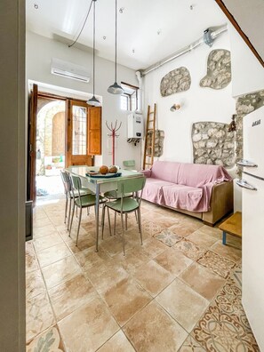 Uma sala de jantar com mesa e cadeiras, um sofá rosa e uma parede de pedra.