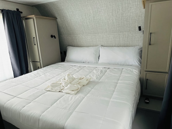 A hotel room with a bed, a wardrobe, and a headboard.