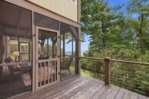 A wooden deck with a glass door leading to an outdoor seating area with a table and chairs.