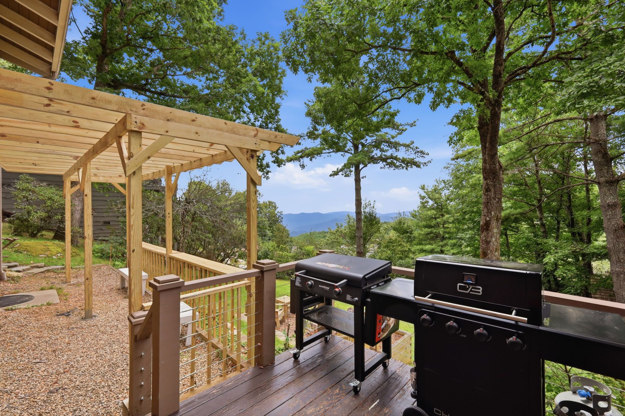 A wooden deck with a barbecue grill and a pergola.