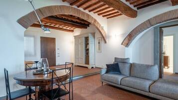 Una stanza con un tavolo rotondo in legno, sedie, un divano e un soffitto con travi a vista.