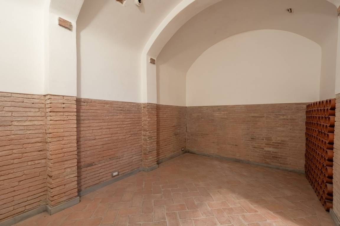 A room with brick walls, a tiled floor, and an arched ceiling.