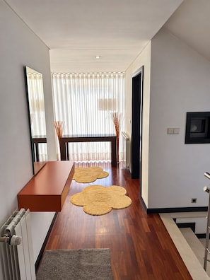 A modern interior with a wooden floor, a long table, and a large mirror. - House with a Pool and Garden Near the Beach (Fão)