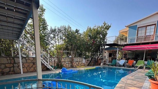 Piscina com muro de pedra e área coberta com guarda-corpo.