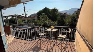 Uma varanda com vista para uma piscina, mesa com cadeiras e um toldo.