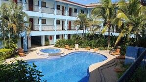A hotel with a swimming pool surrounded by palm trees and lounge chairs. - Marina Loft Studio # 218 (Sardinal)