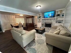 Una sala de estar con dos sofás, una mesa de centro y un televisor sobre un mueble.