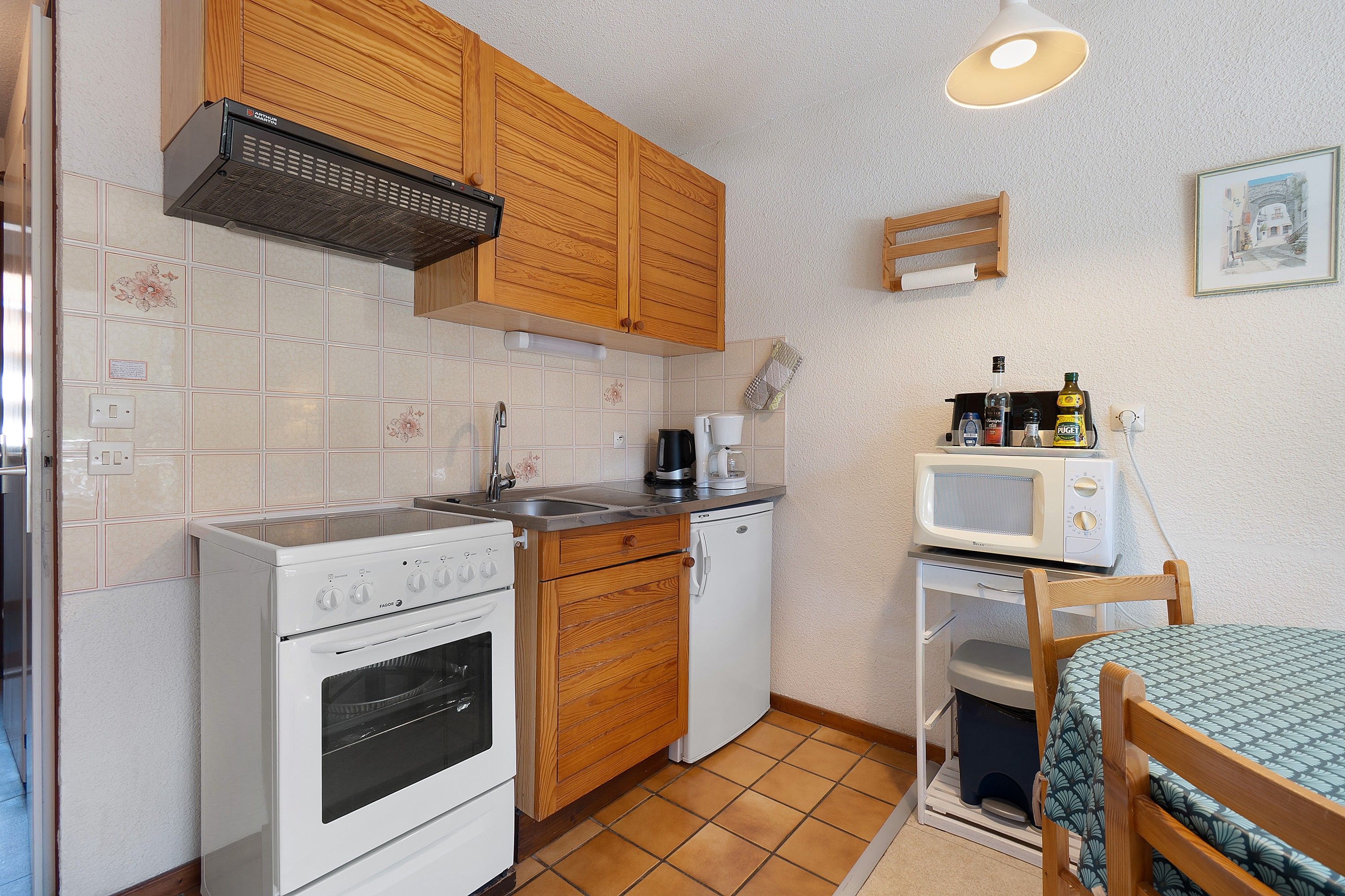 A compact kitchen with a stove, oven, microwave, and a small sink.