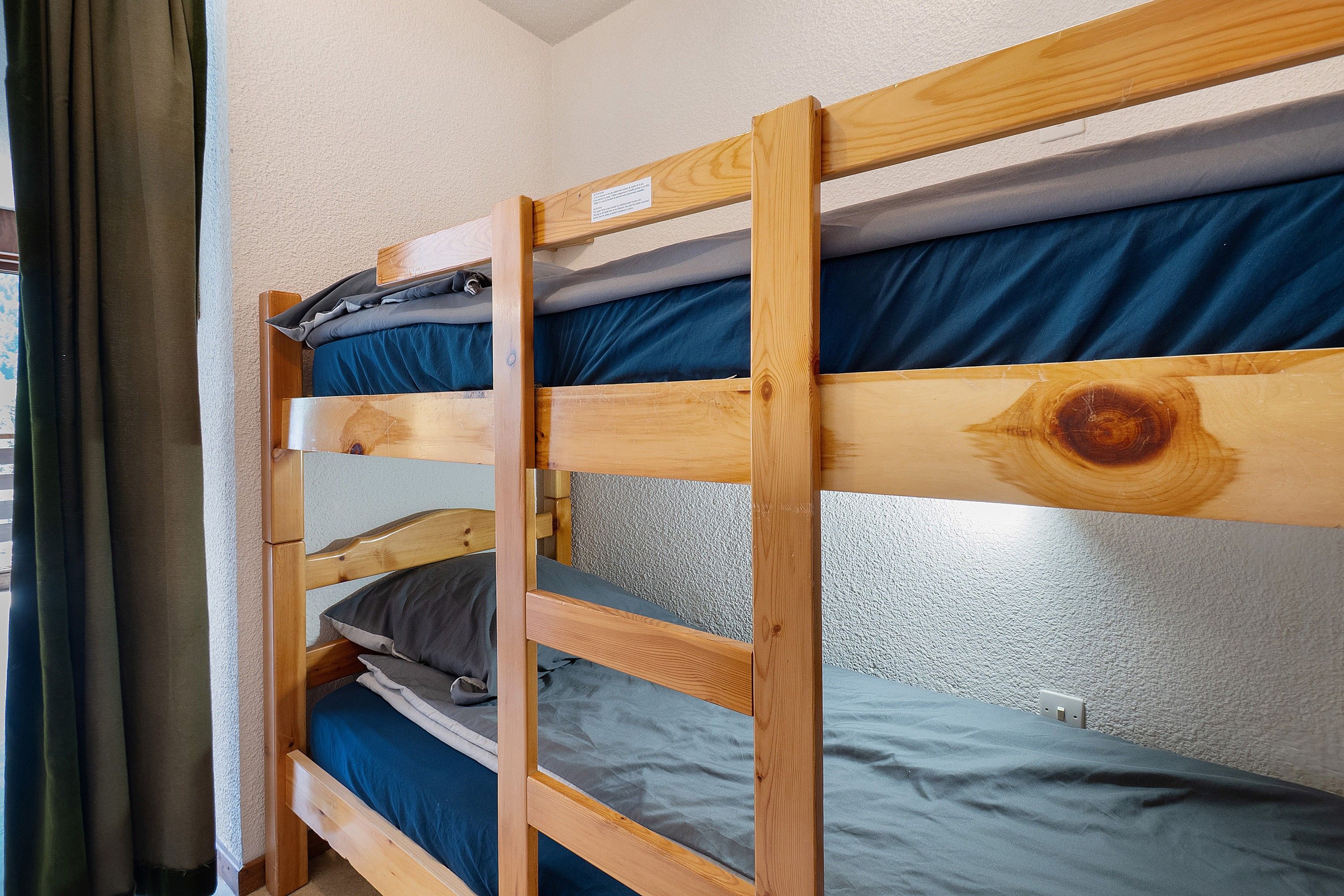 Ein Stockbett mit zwei Etagen, jede mit einem Kopfkissen und einer Decke.