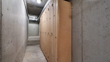 Een smalle gang met kasten aan de ene kant en een betonnen muur aan de andere kant.