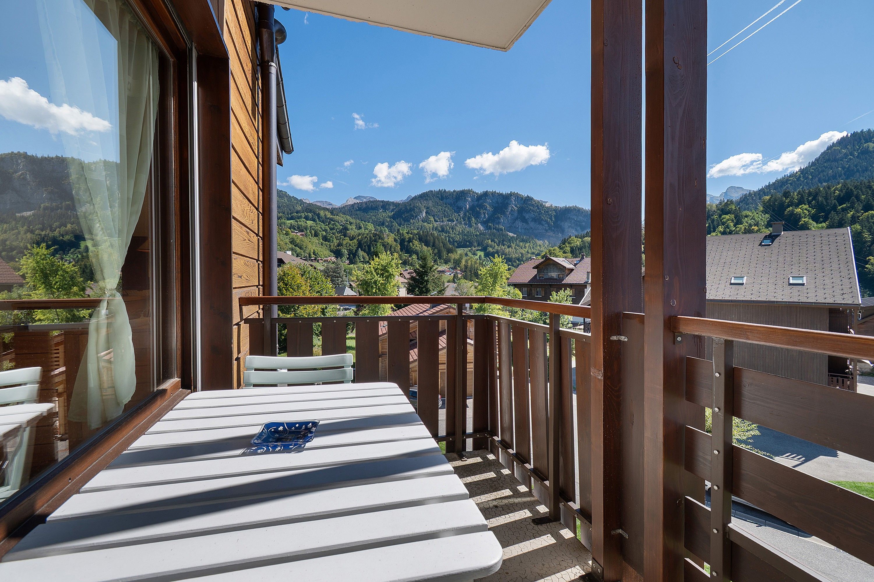 Un balcon avec une table et des chaises, donnant sur un paysage montagneux.