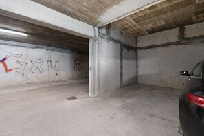 En parkeringsgarage med betonvægge, en bil parkeret til højre og graffiti på venstre væg.