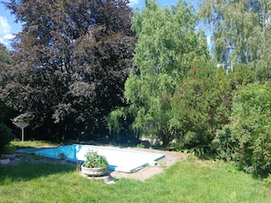Ein Schwimmbad, umgeben von Gras und Bäumen.
