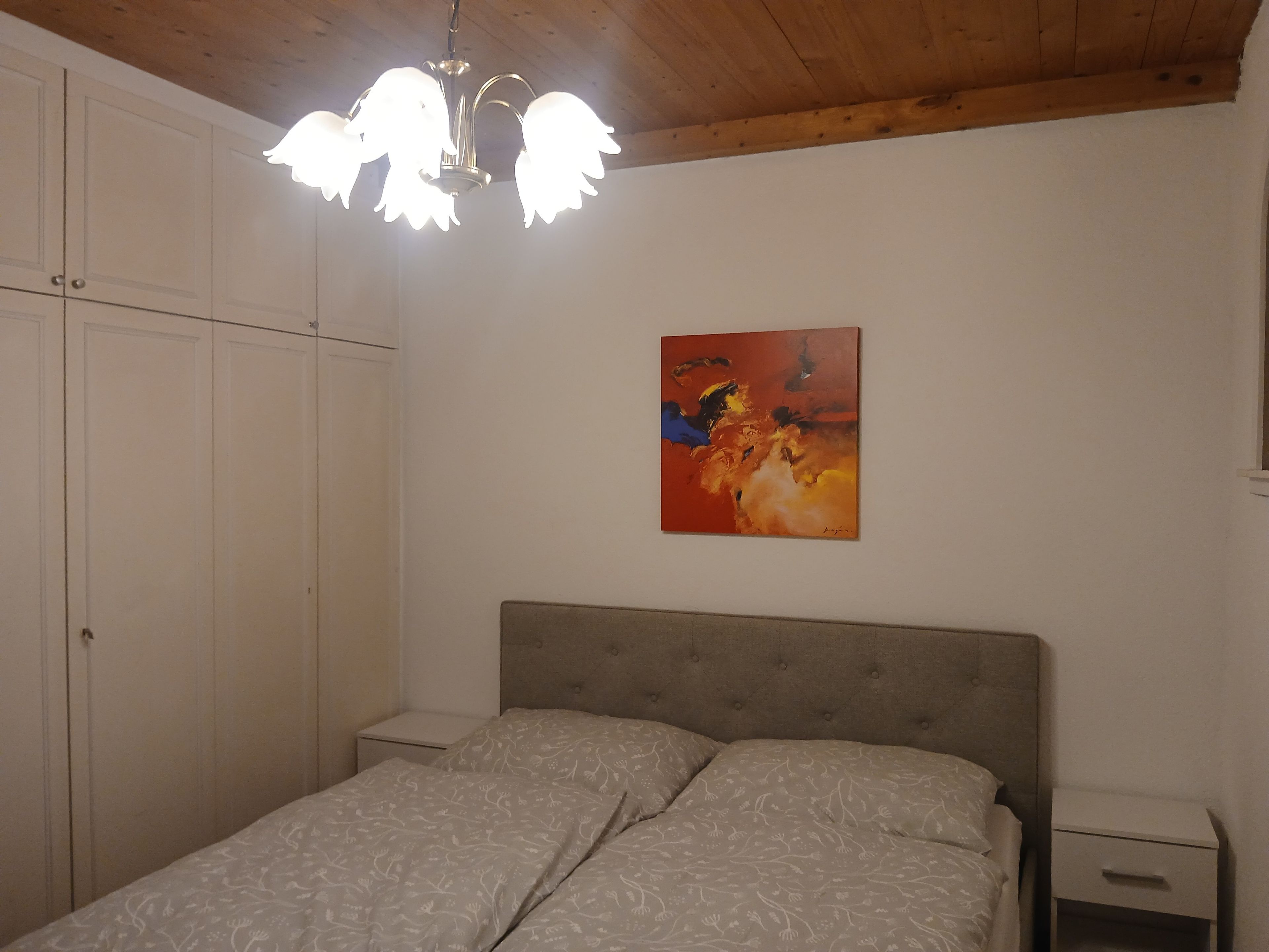 Une chambre à coucher avec un lit, une table de chevet, une armoire et un tableau au mur.