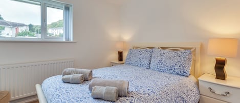 Une chambre à coucher avec un lit, deux lampes de chevet, une fenêtre et un radiateur.