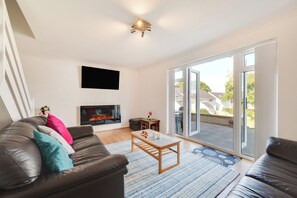 Ein Wohnzimmer mit Kamin, einer Couch, einem Couchtisch und einem großen Fenster.