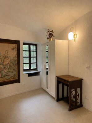 A room with a large window, a white cabinet, a wooden table, and a wall-mounted light fixture.