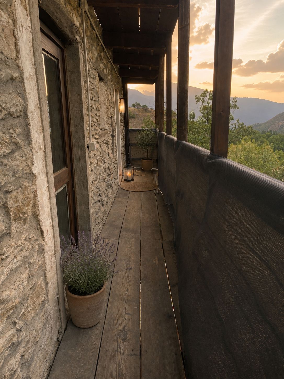Un balcon en bois avec un mur en pierre, un pot de fleurs et une vue sur le paysage.