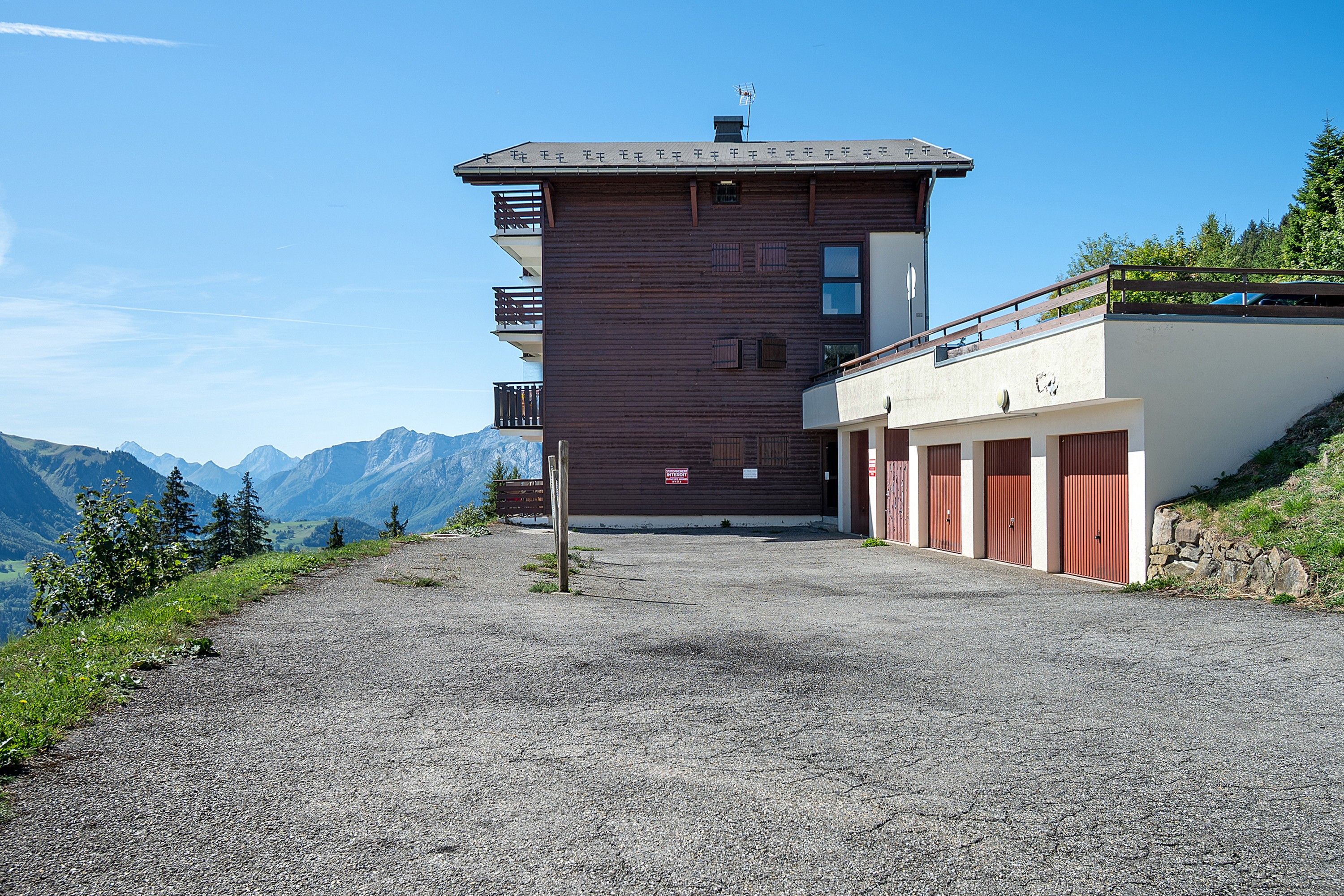 Ein Gebäude mit einem geneigten Dach, einer Holzfassade und einem Kiesweg, der davorführt.