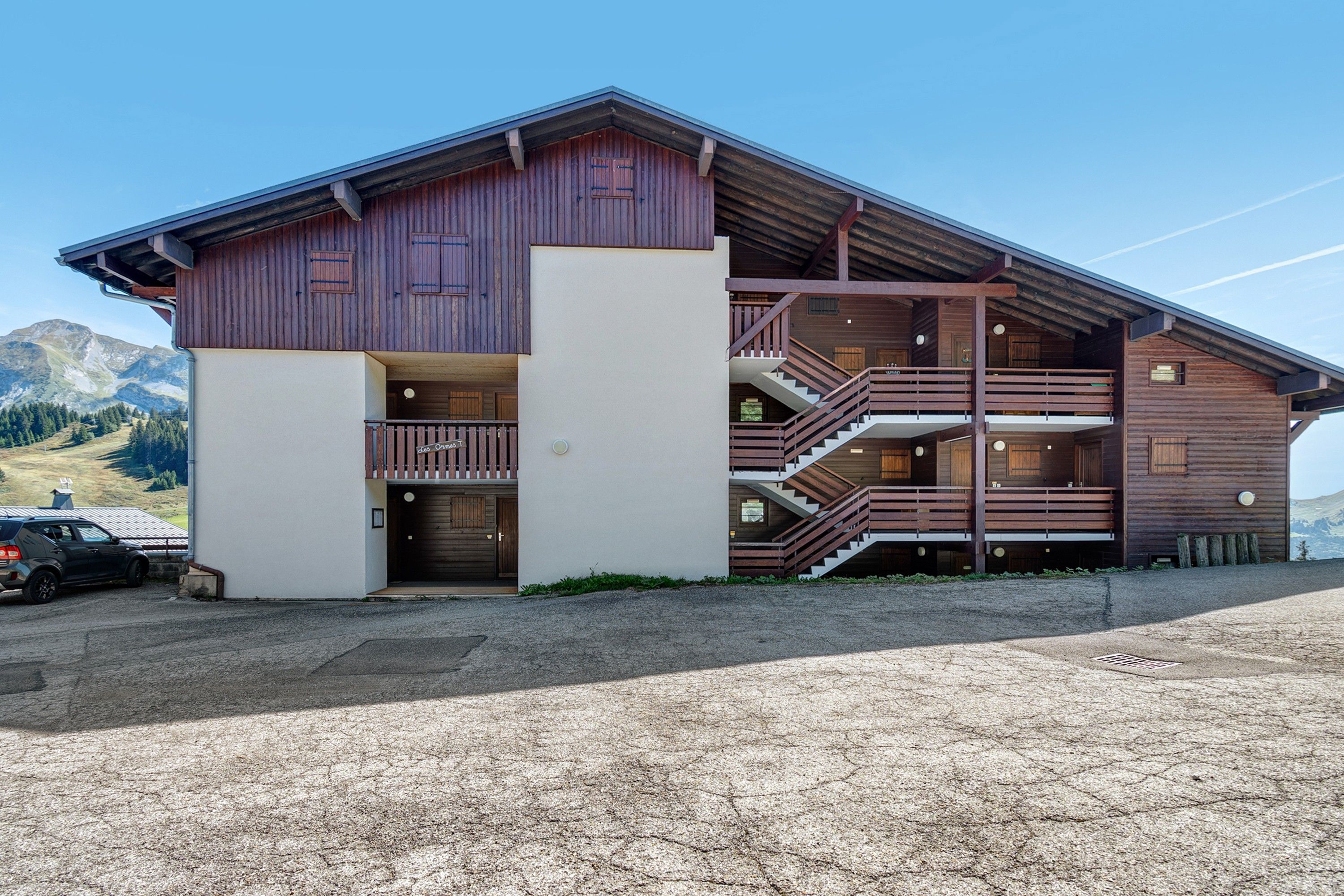 Een gebouw van hout met twee verdiepingen, een balkon en een trap.
