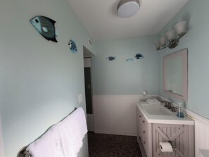 A bathroom with a white vanity, a mirror, a towel rack, and decorative fish wall art. - 1-bedroom bungalow in Jensen Beach, a view of 
 intercoastal & Hutchinson Island (Jensen Beach)